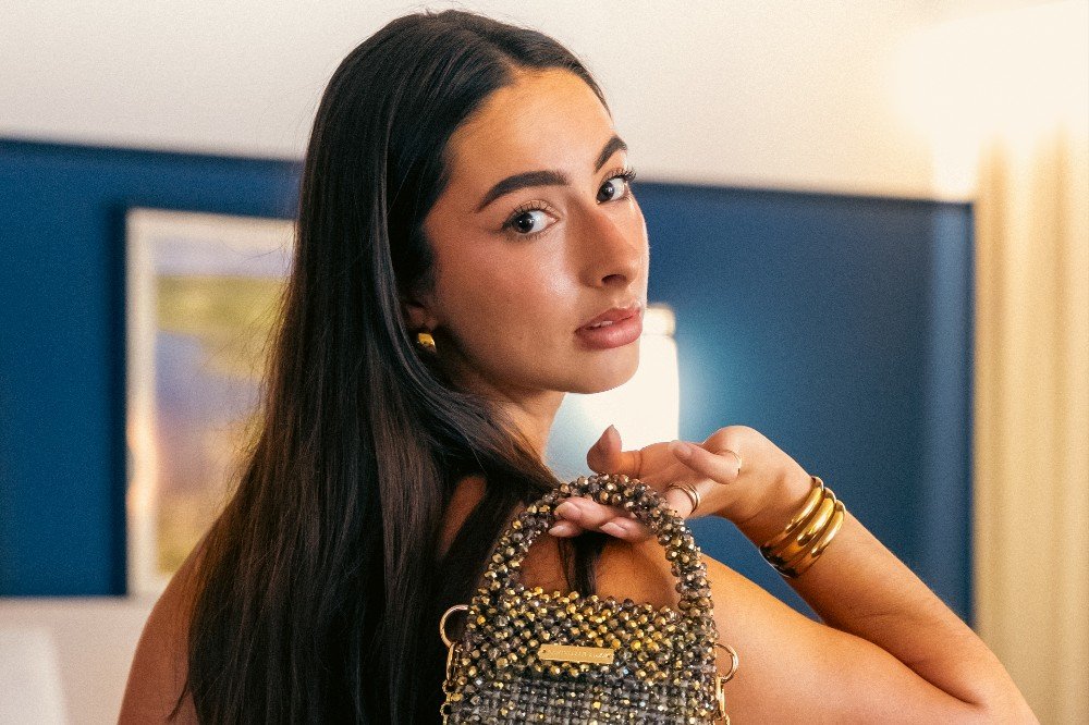 Jeune femme au regard caméra tenant un sac à main perlé